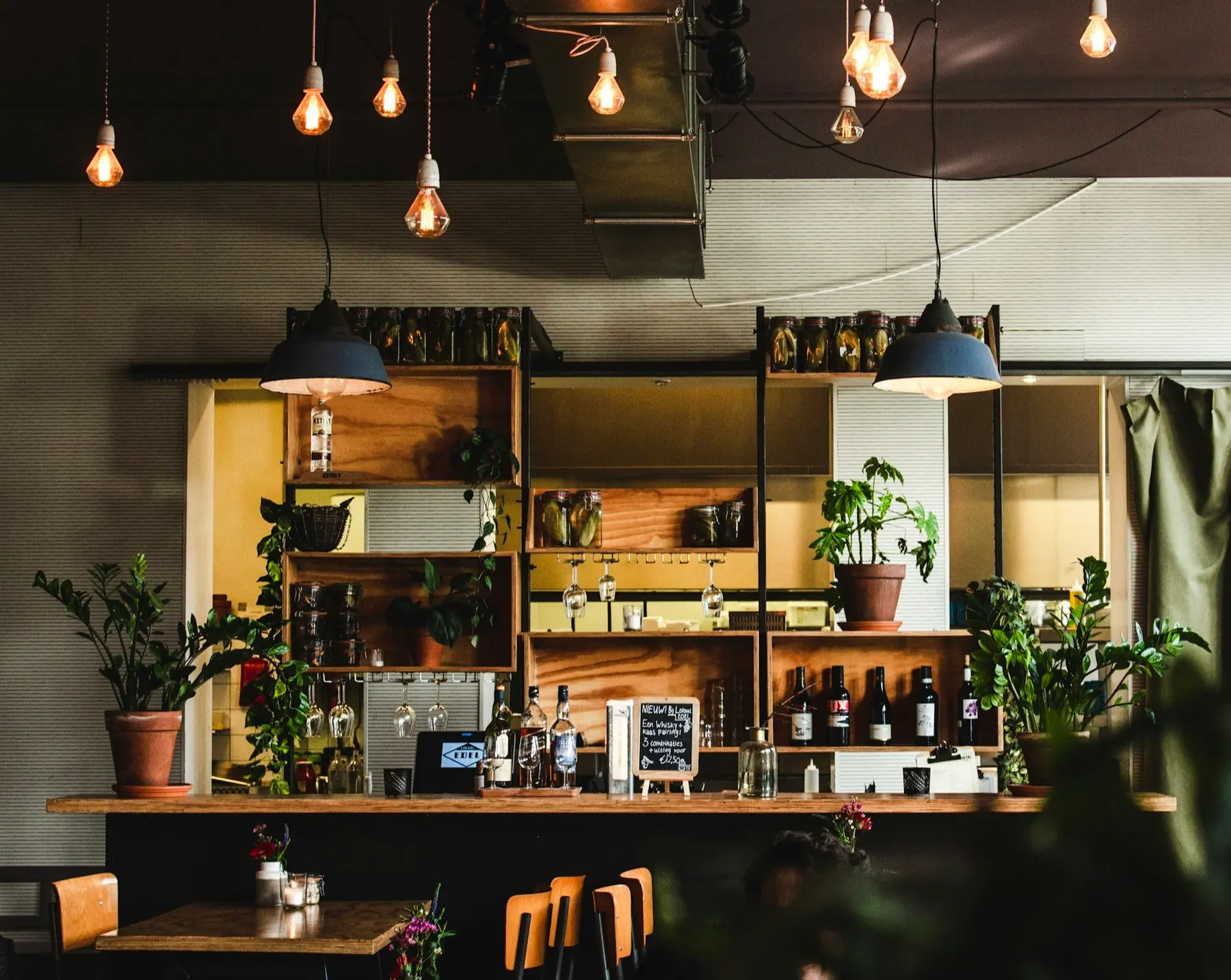 Koffiebar met open houten kasten, planten en warm licht