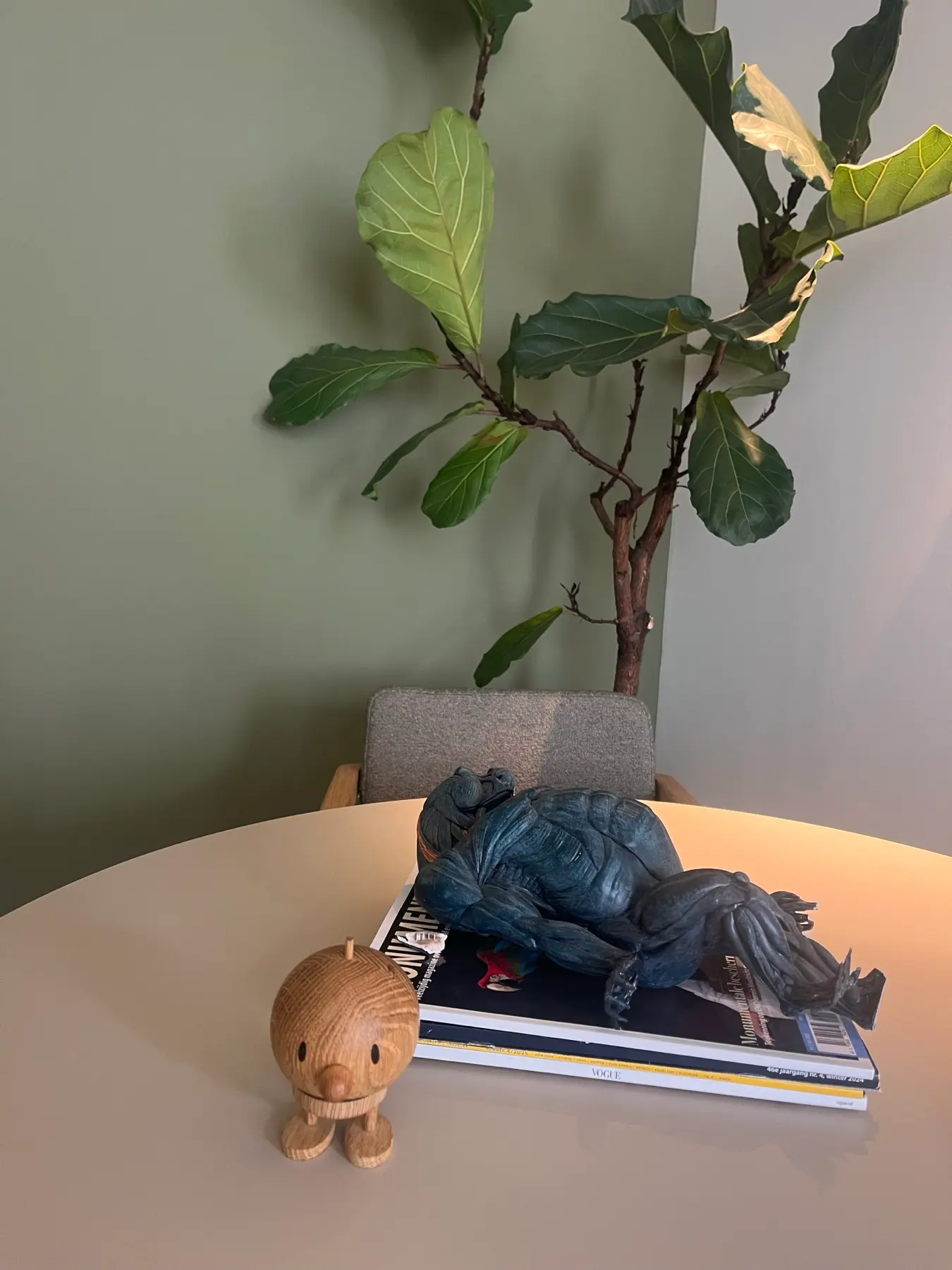 Styling op tafel met tijdschriften, sculptuur en vioolbladplant